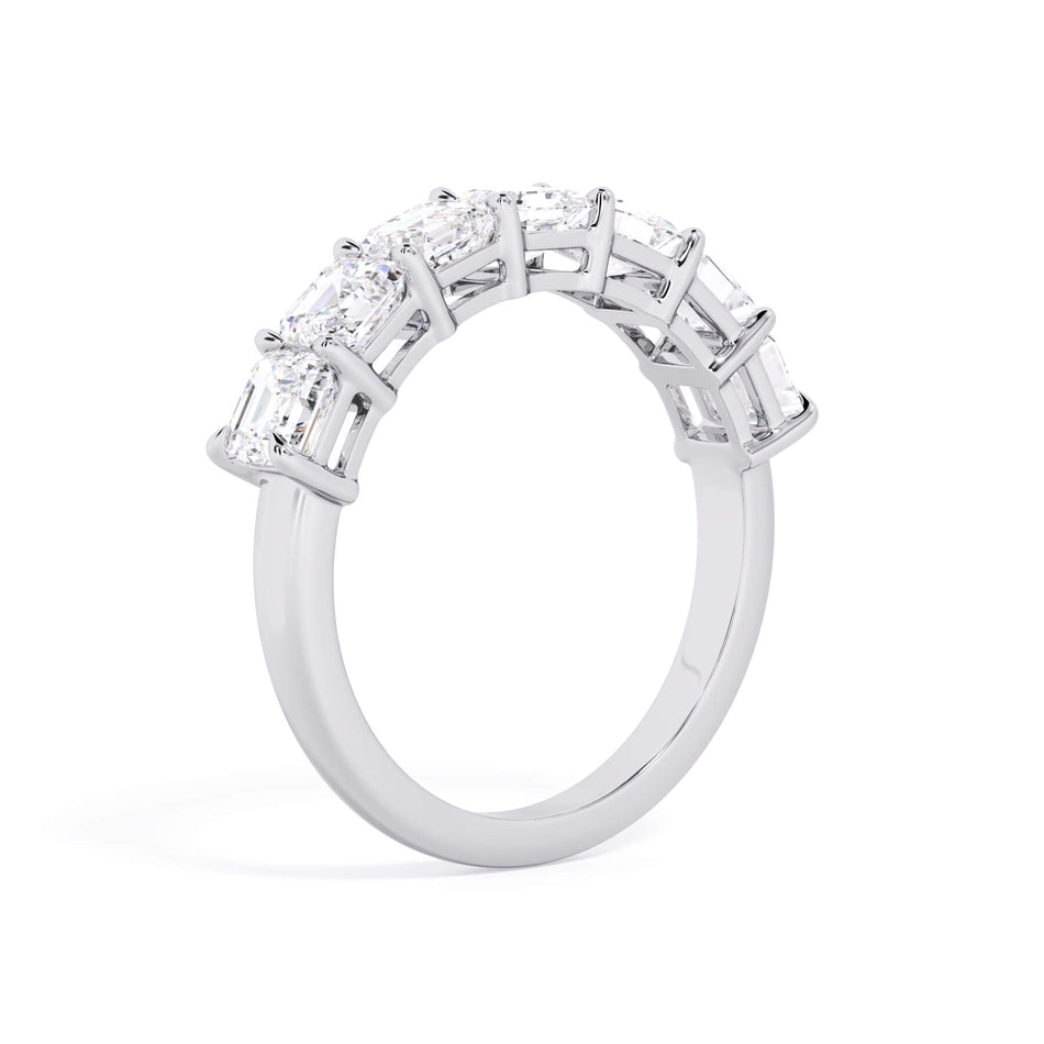 A picture of a seven stone diamond wedding ring with asscher cut diamonds that are shared prong set in white gold or platinum on a white background with a slightly angled, through the finger view.
