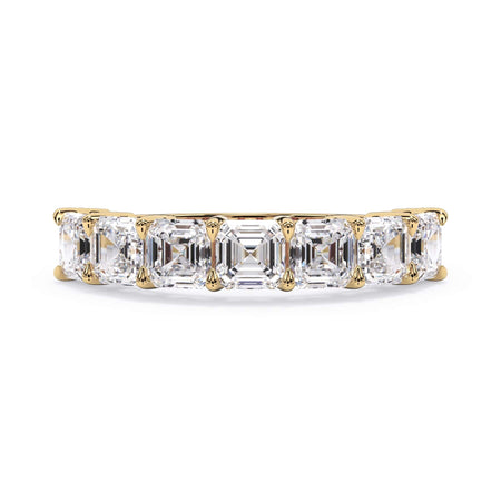 A picture of a seven stone diamond wedding ring with asscher cut diamonds that are shared prong set in yellow gold on a white background with the ring facing forward, lying down.