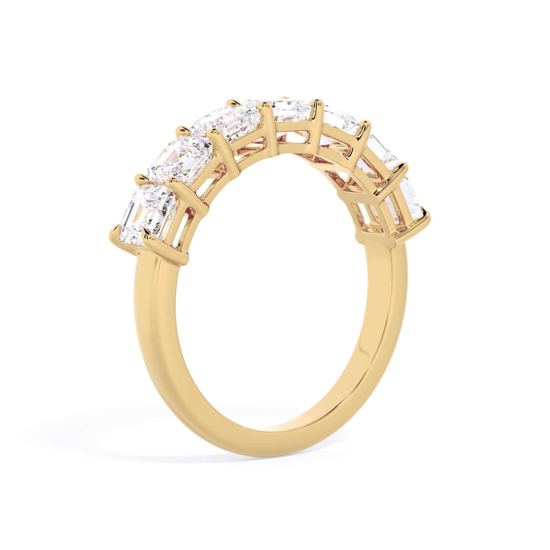 A picture of a seven stone diamond wedding ring with asscher cut diamonds that are shared prong set in yellow gold on a white background with a slightly angled, through the finger view.