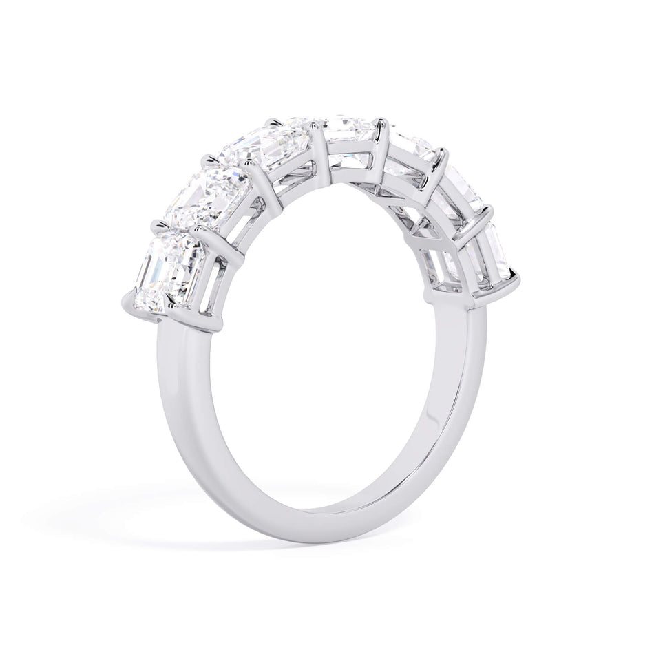 A picture of a seven stone diamond wedding ring with asscher cut diamonds that are shared prong set in white gold or platinum on a white background with a slightly angled, through the finger view.