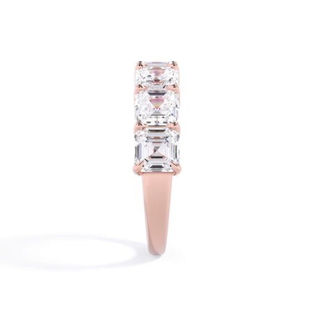 A picture of a seven stone diamond wedding ring with asscher cut diamonds that are shared prong set in rose gold on a white background with a side profile view.