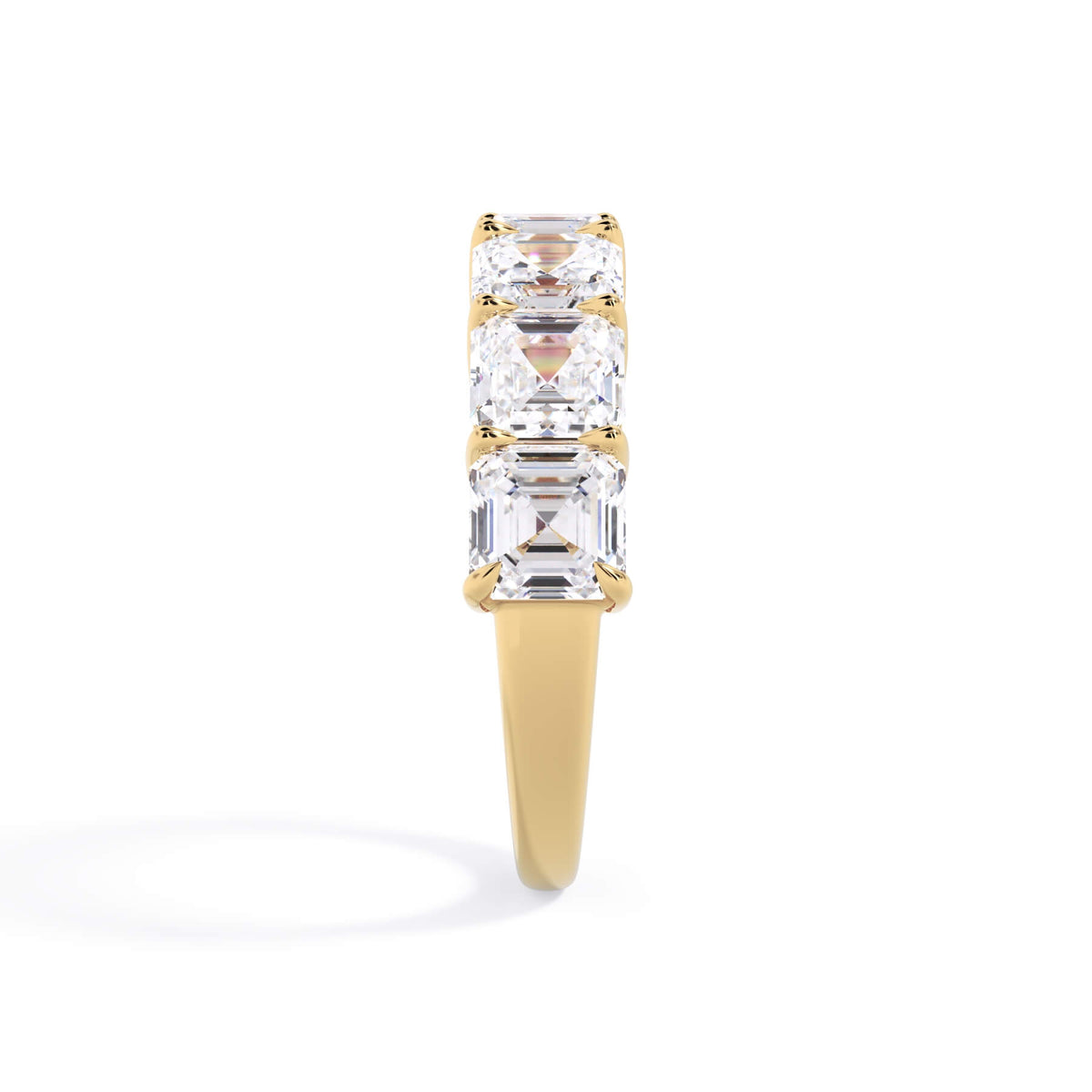 A picture of a seven stone diamond wedding ring with asscher cut diamonds that are shared prong set in yellow gold on a white background with the ring facing forward, lying down.