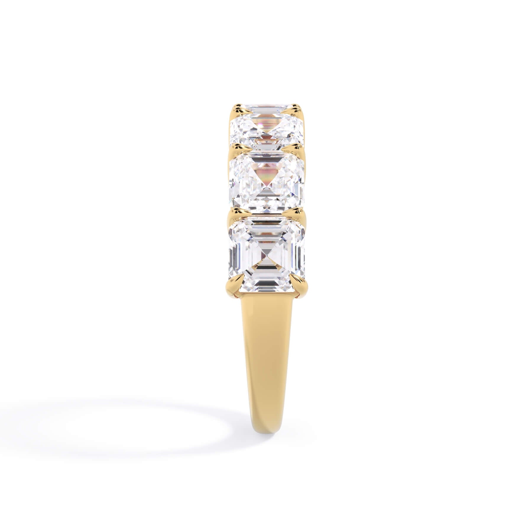 A picture of a seven stone diamond wedding ring with asscher cut diamonds that are shared prong set in yellow gold on a white background with the ring facing forward, lying down.
