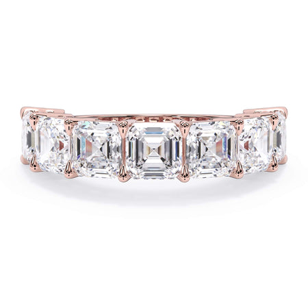 A picture of a seven stone diamond wedding ring with asscher cut diamonds that are shared prong set in rose gold on a white background with the ring facing forward, lying down.