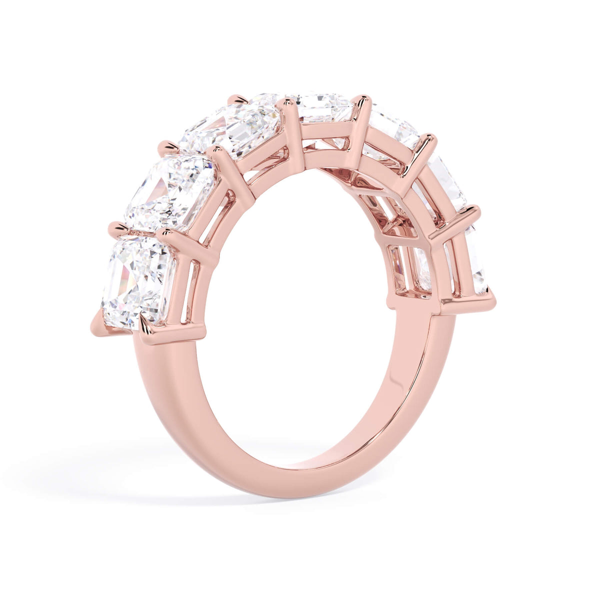 A picture of a seven stone diamond wedding ring with asscher cut diamonds that are shared prong set in rose gold on a white background with a slightly angled, through the finger view.