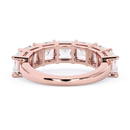 A picture of a seven stone diamond wedding ring with asscher cut diamonds that are shared prong set in rose gold on a white background with a view of the underside of the ring.