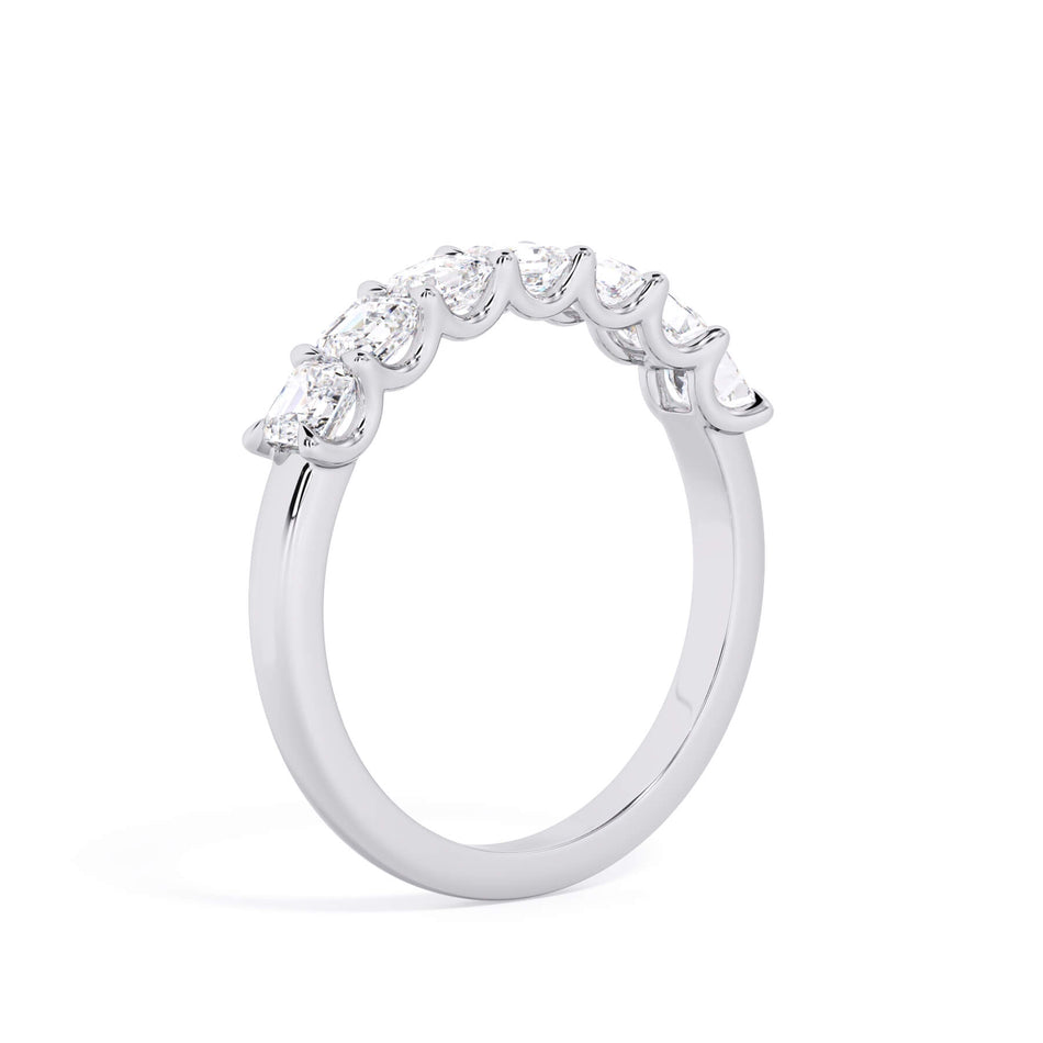 A picture of a seven stone diamond wedding ring with asscher cut diamonds that are U prong set in white gold or platinum on a white background with a slightly angled, through the finger view.