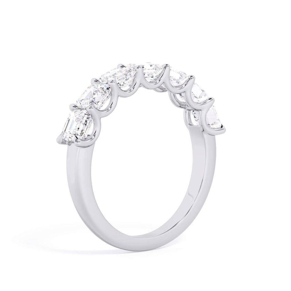 A picture of a seven stone diamond wedding ring with asscher cut diamonds that are U prong set in white gold or platinum on a white background with a slightly angled, through the finger view.