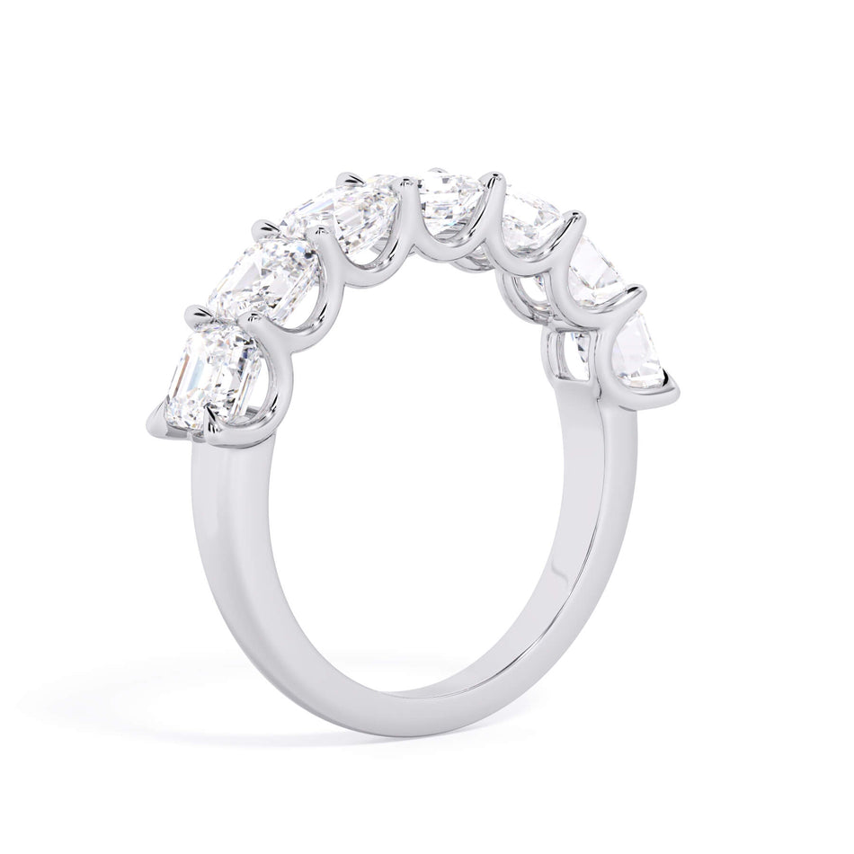 A picture of a seven stone diamond wedding ring with asscher cut diamonds that are U prong set in white gold or platinum on a white background with a slightly angled, through the finger view.