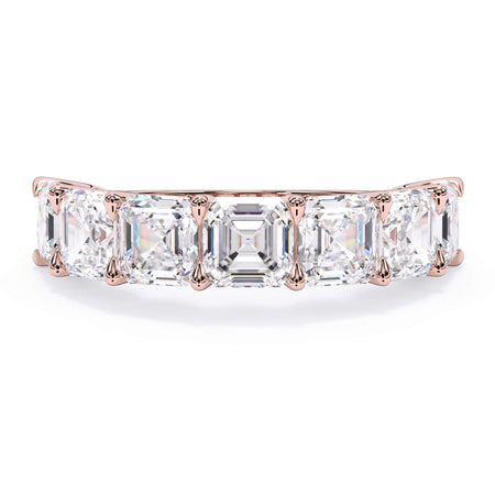 A picture of a seven stone diamond wedding ring with asscher cut diamonds that are U prong set in rose gold on a white background with the ring facing forward, lying down.