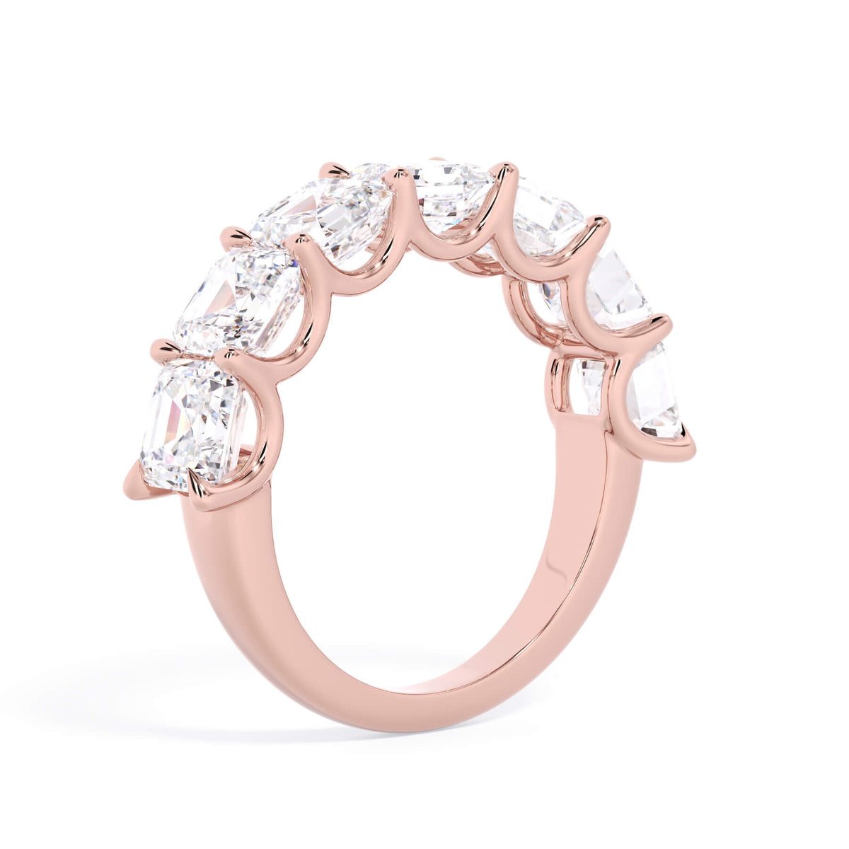 A picture of a seven stone diamond wedding ring with asscher cut diamonds that are U prong set in rose gold on a white background with a slightly angled, through the finger view.