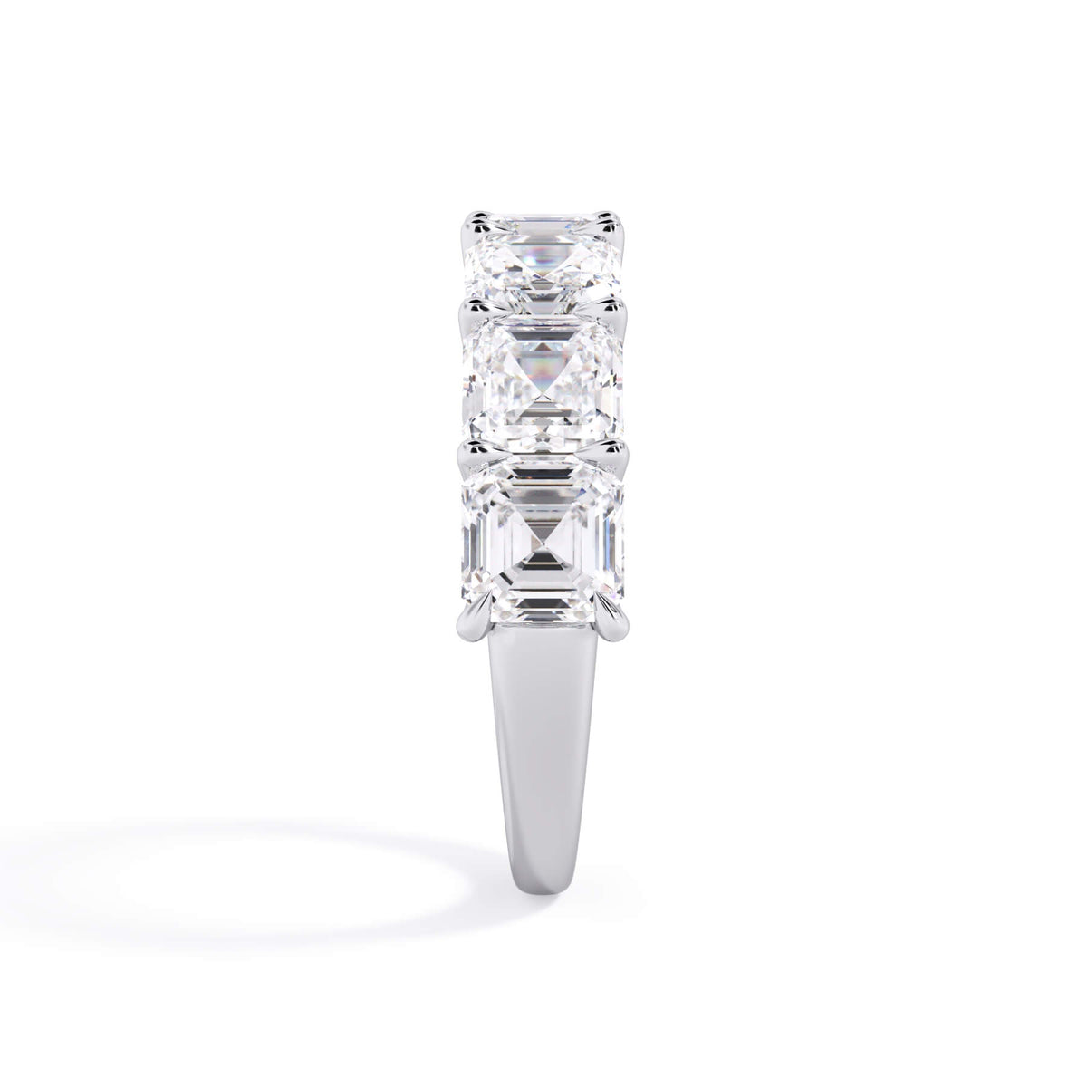 A picture of a seven stone diamond wedding ring with asscher cut diamonds that are U prong set in white gold or platinum on a white background with a side profile view.