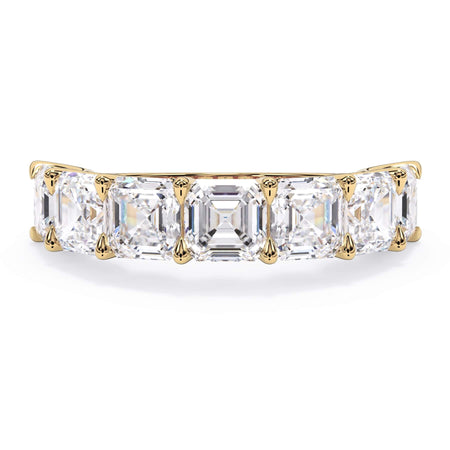 A picture of a seven stone diamond wedding ring with asscher cut diamonds that are U prong set in yellow gold on a white background with the ring facing forward, lying down.