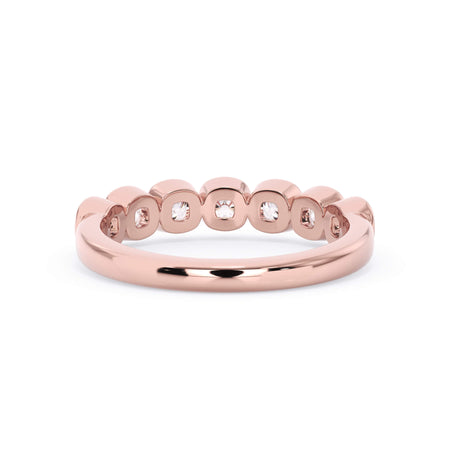 A picture of a seven stone diamond wedding ring with cushion cut diamonds that are bezel set in rose gold on a white background with a view of the underside of the ring.