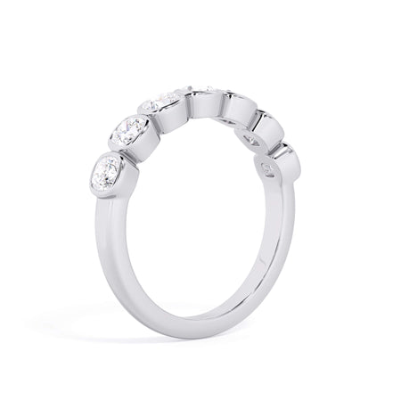 A picture of a seven stone diamond wedding ring with cushion cut diamonds that are bezel set in white gold or platinum on a white background with a slightly angled, through the finger view.