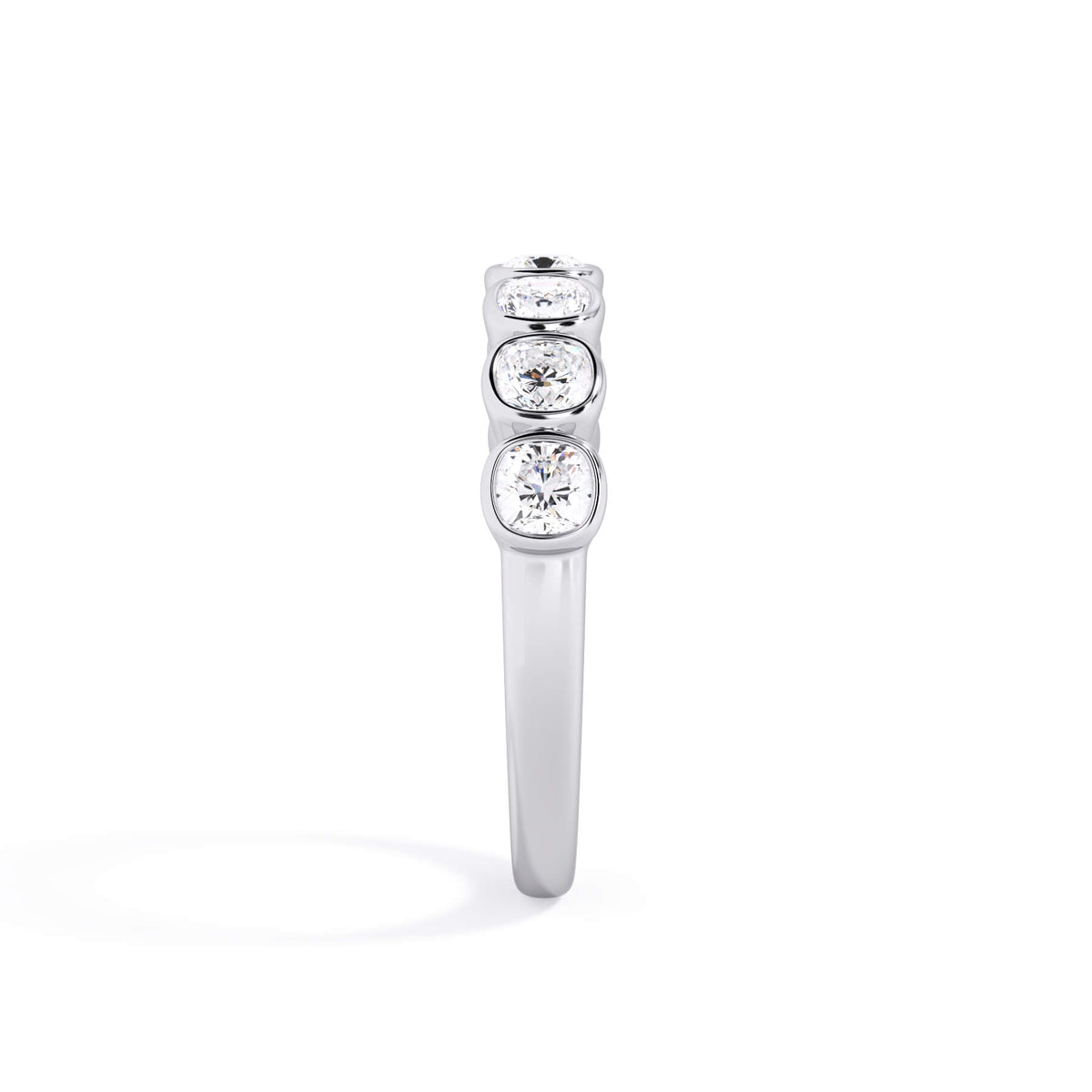 A picture of a seven stone diamond wedding ring with cushion cut diamonds that are bezel set in white gold or platinum on a white background with a side profile view.