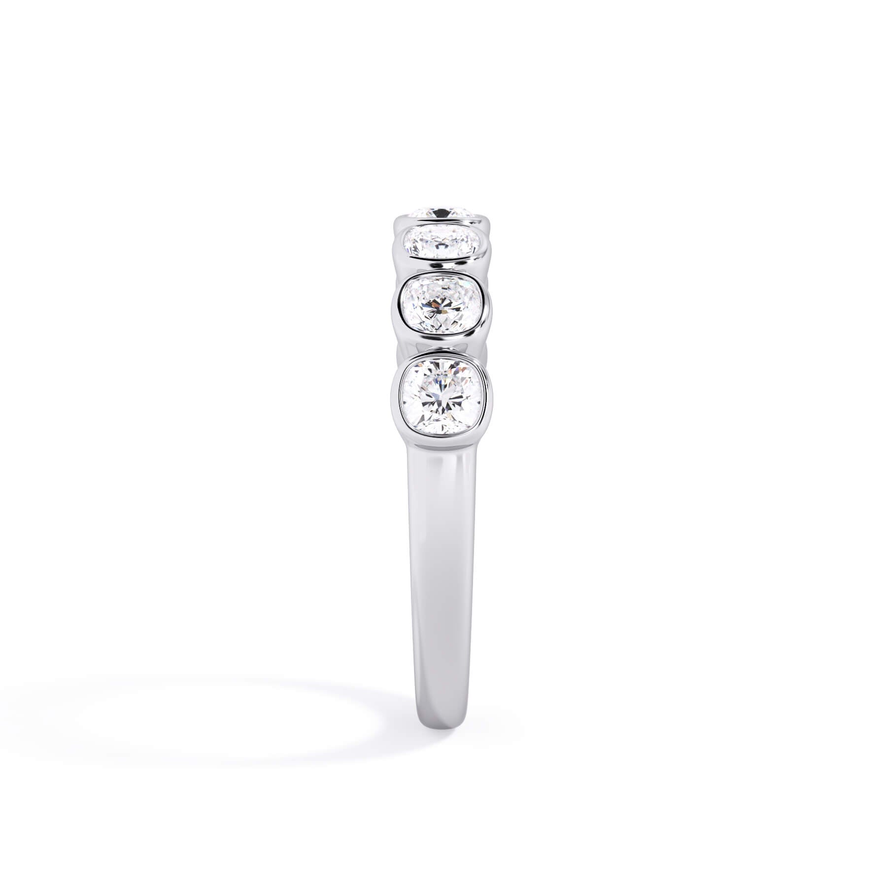 A picture of a seven stone diamond wedding ring with cushion cut diamonds that are bezel set in white gold or platinum on a white background with a side profile view.