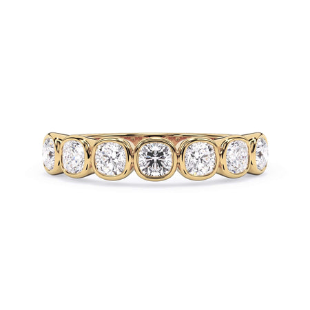 A picture of a seven stone diamond wedding ring with cushion cut diamonds that are bezel set in yellow gold on a white background with the ring facing forward, lying down.