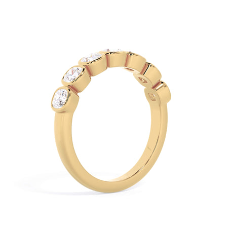 A picture of a seven stone diamond wedding ring with cushion cut diamonds that are bezel set in yellow gold on a white background with a slightly angled, through the finger view.