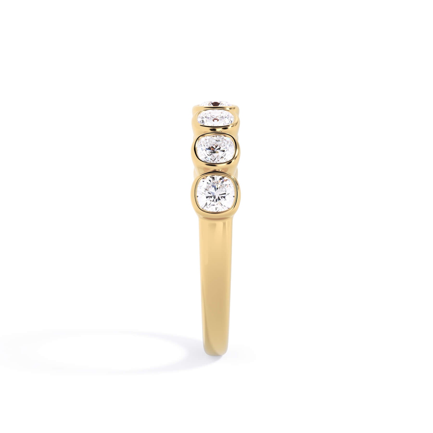 A picture of a seven stone diamond wedding ring with cushion cut diamonds that are bezel set in yellow gold on a white background with a side profile view.
