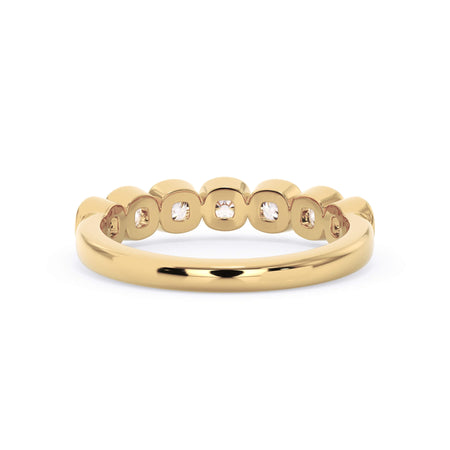A picture of a seven stone diamond wedding ring with cushion cut diamonds that are bezel set in yellow gold on a white background with a view of the underside of the ring.