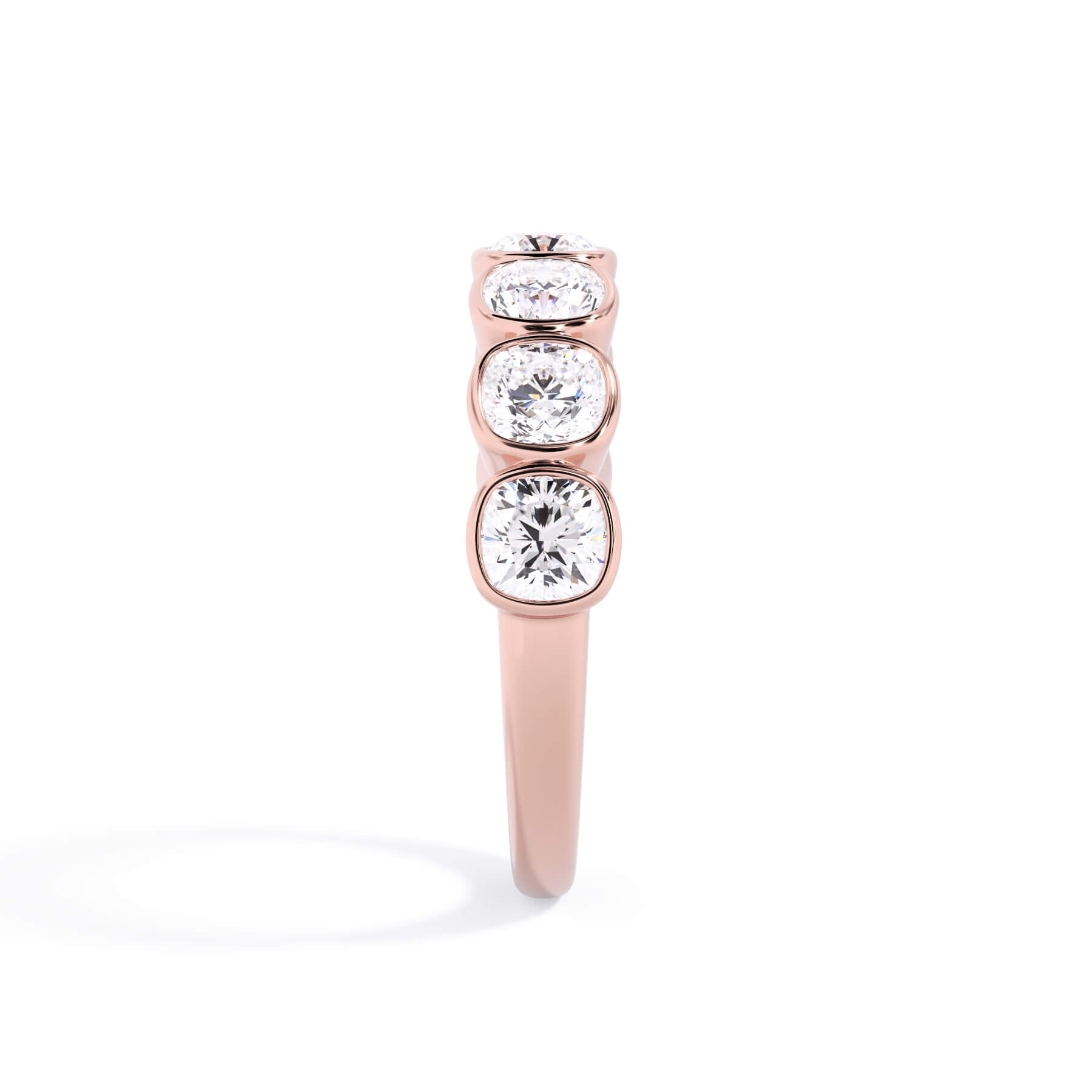 A picture of a seven stone diamond wedding ring with cushion cut diamonds that are bezel set in rose gold on a white background with the ring facing forward, lying down.