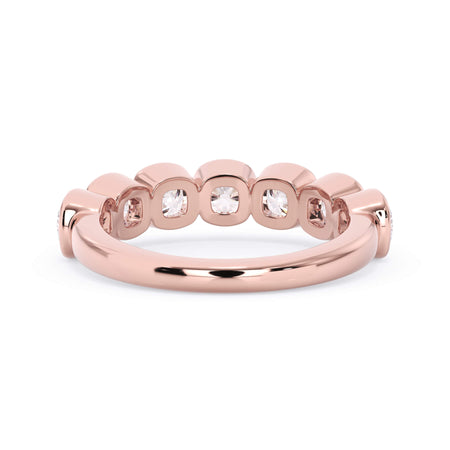 A picture of a seven stone diamond wedding ring with cushion cut diamonds that are bezel set in rose gold on a white background with the ring facing forward, lying down.
