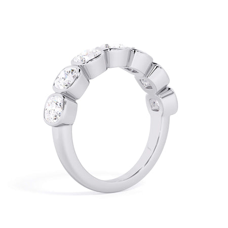 A picture of a seven stone diamond wedding ring with cushion cut diamonds that are bezel set in white gold or platinum on a white background with the ring facing forward, lying down.