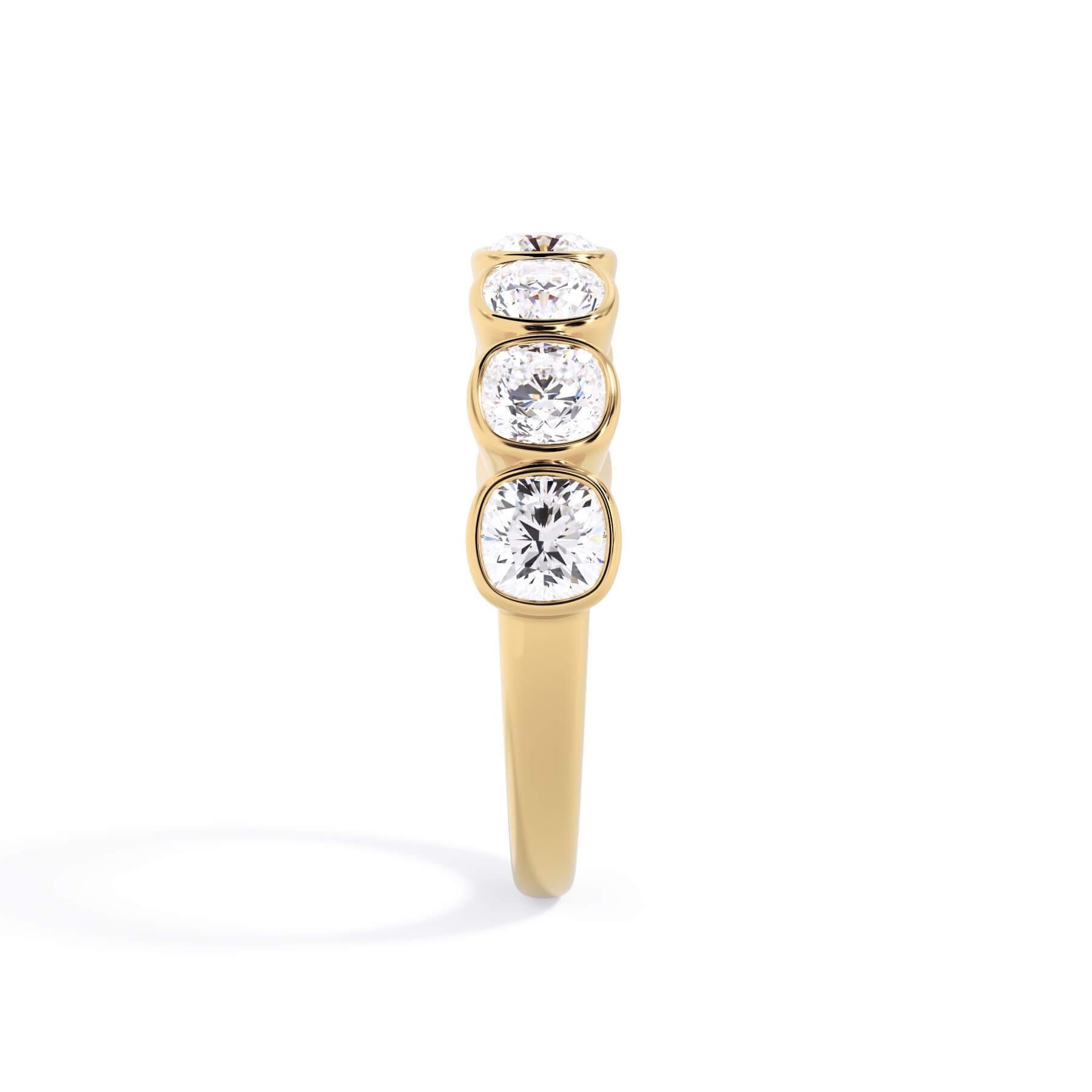 A picture of a seven stone diamond wedding ring with cushion cut diamonds that are bezel set in yellow gold on a white background with a side profile view.