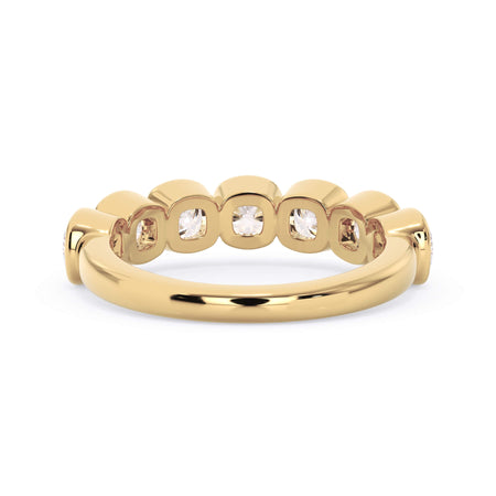 A picture of a seven stone diamond wedding ring with cushion cut diamonds that are bezel set in yellow gold on a white background with a view of the underside of the ring.
