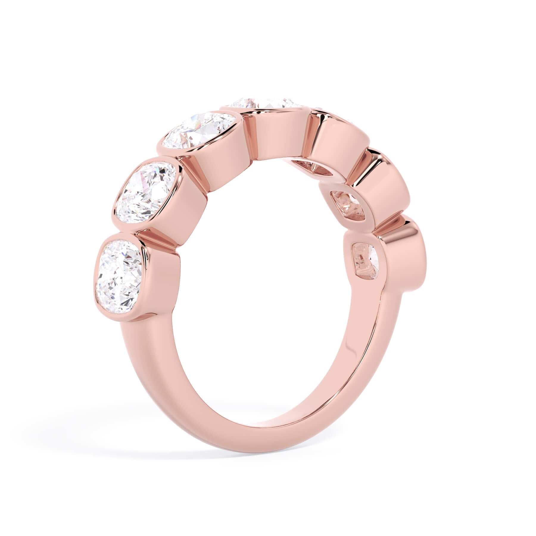 A picture of a seven stone diamond wedding ring with cushion cut diamonds that are bezel set in rose gold on a white background with a slightly angled, through the finger view.