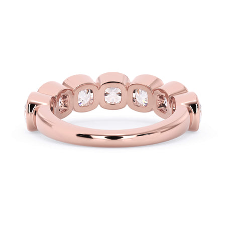 A picture of a seven stone diamond wedding ring with cushion cut diamonds that are bezel set in rose gold on a white background with a view of the underside of the ring.