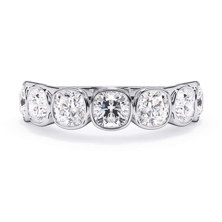 A picture of a seven stone diamond wedding ring with cushion cut diamonds that are bezel set in white gold or platinum on a white background with the ring facing forward, lying down.