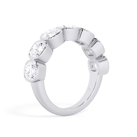 A picture of a seven stone diamond wedding ring with cushion cut diamonds that are bezel set in white gold or platinum on a white background with a slightly angled, through the finger view.