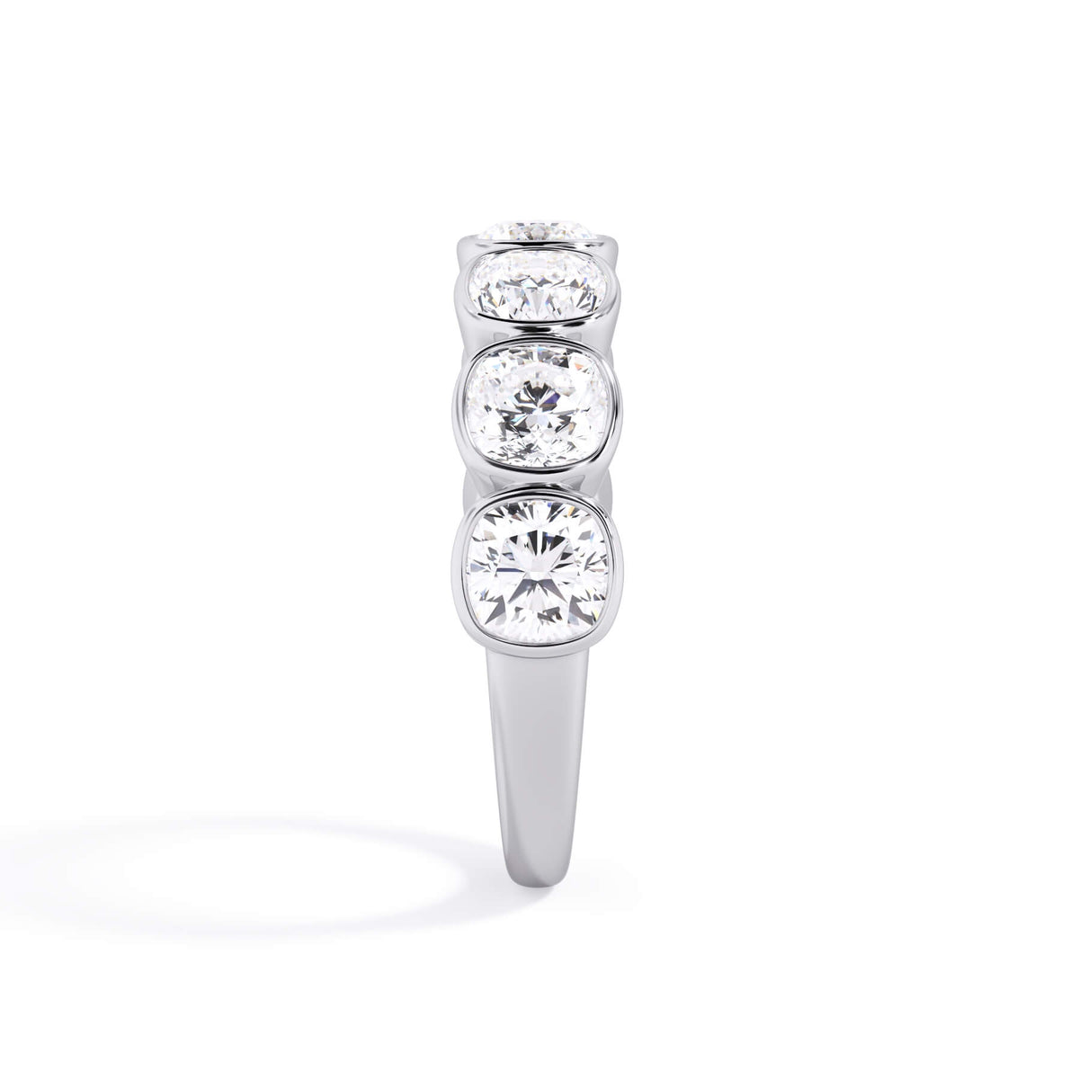A picture of a seven stone diamond wedding ring with cushion cut diamonds that are bezel set in white gold or platinum on a white background with a side profile view.