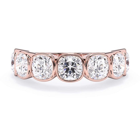 A picture of a seven stone diamond wedding ring with cushion cut diamonds that are bezel set in rose gold on a white background with the ring facing forward, lying down.