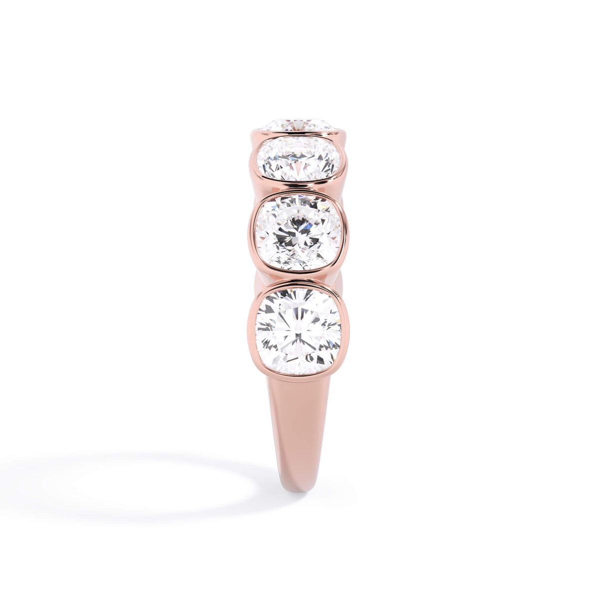 A picture of a seven stone diamond wedding ring with cushion cut diamonds that are bezel set in rose gold on a white background with a side profile view.