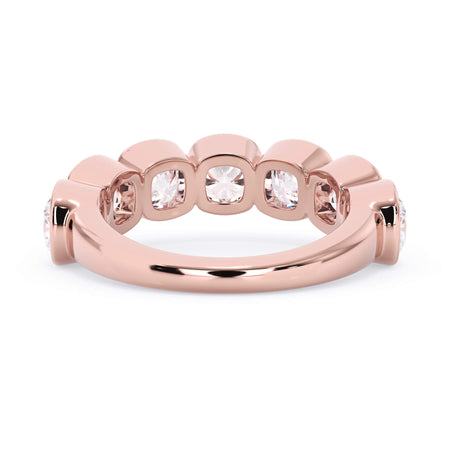 A picture of a seven stone diamond wedding ring with cushion cut diamonds that are bezel set in rose gold on a white background with a view of the underside of the ring.