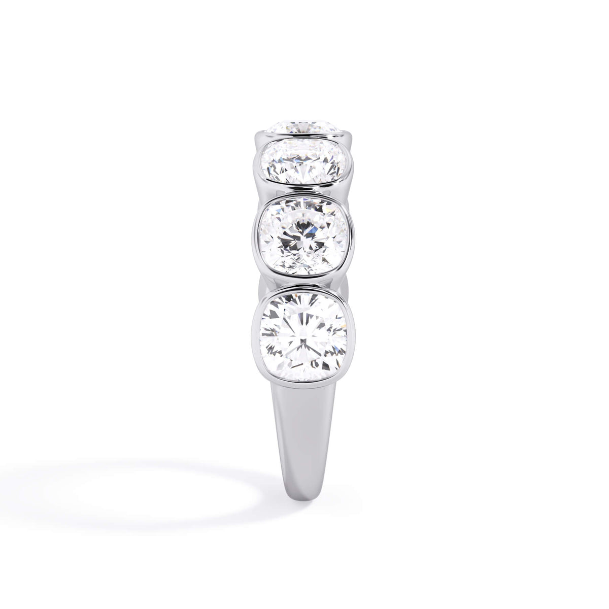 A picture of a seven stone diamond wedding ring with cushion cut diamonds that are bezel set in white gold or platinum on a white background with a side profile view.