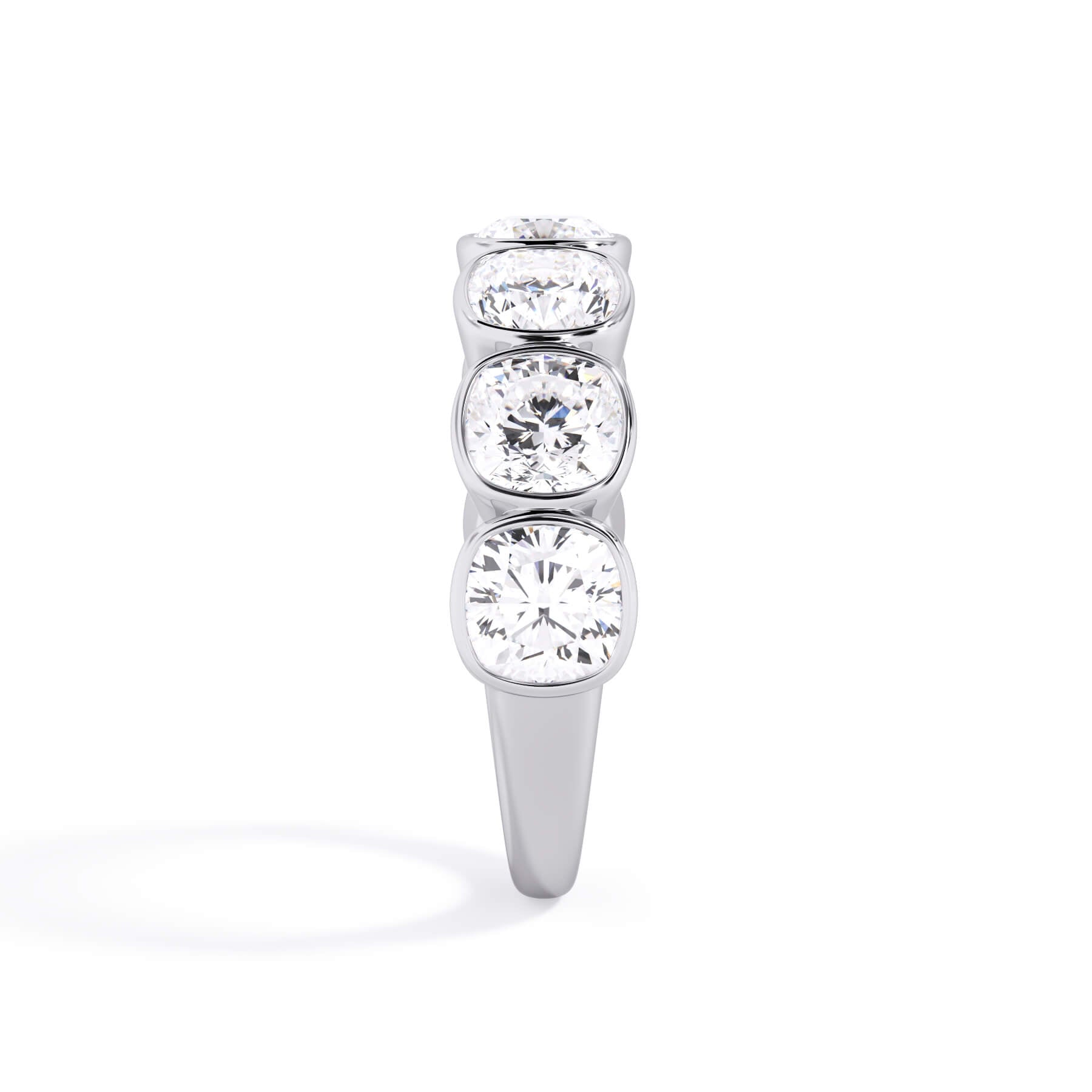 A picture of a seven stone diamond wedding ring with cushion cut diamonds that are bezel set in white gold or platinum on a white background with a side profile view.