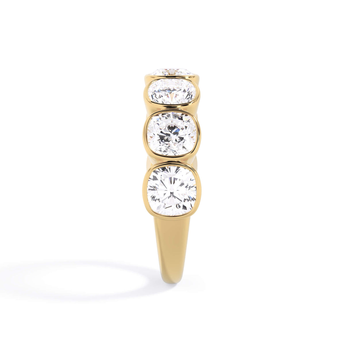 A picture of a seven stone diamond wedding ring with cushion cut diamonds that are bezel set in yellow gold on a white background with a side profile view.