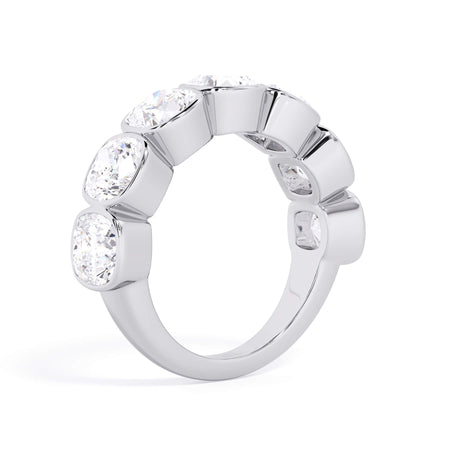 A picture of a seven stone diamond wedding ring with cushion cut diamonds that are bezel set in white gold or platinum on a white background with a slightly angled, through the finger view.