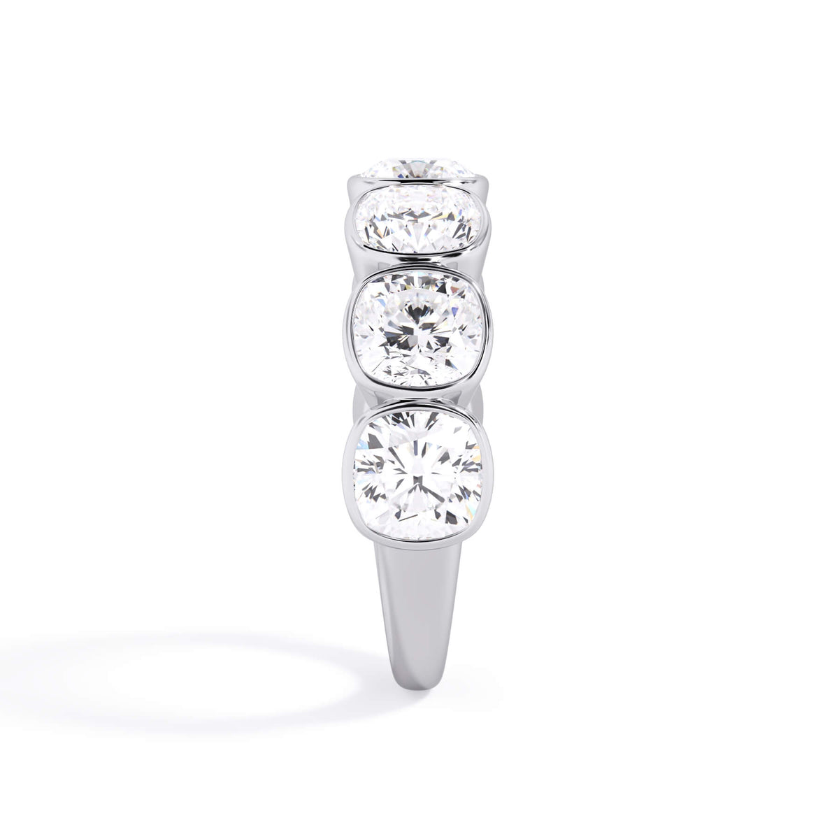 A picture of a seven stone diamond wedding ring with cushion cut diamonds that are bezel set in white gold or platinum on a white background with a side profile view.