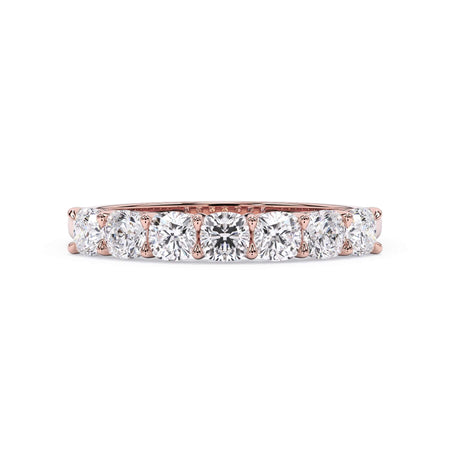 A picture of a seven stone diamond wedding ring with cushion cut diamonds that are shared prong set in rose gold on a white background with the ring facing forward, lying down.