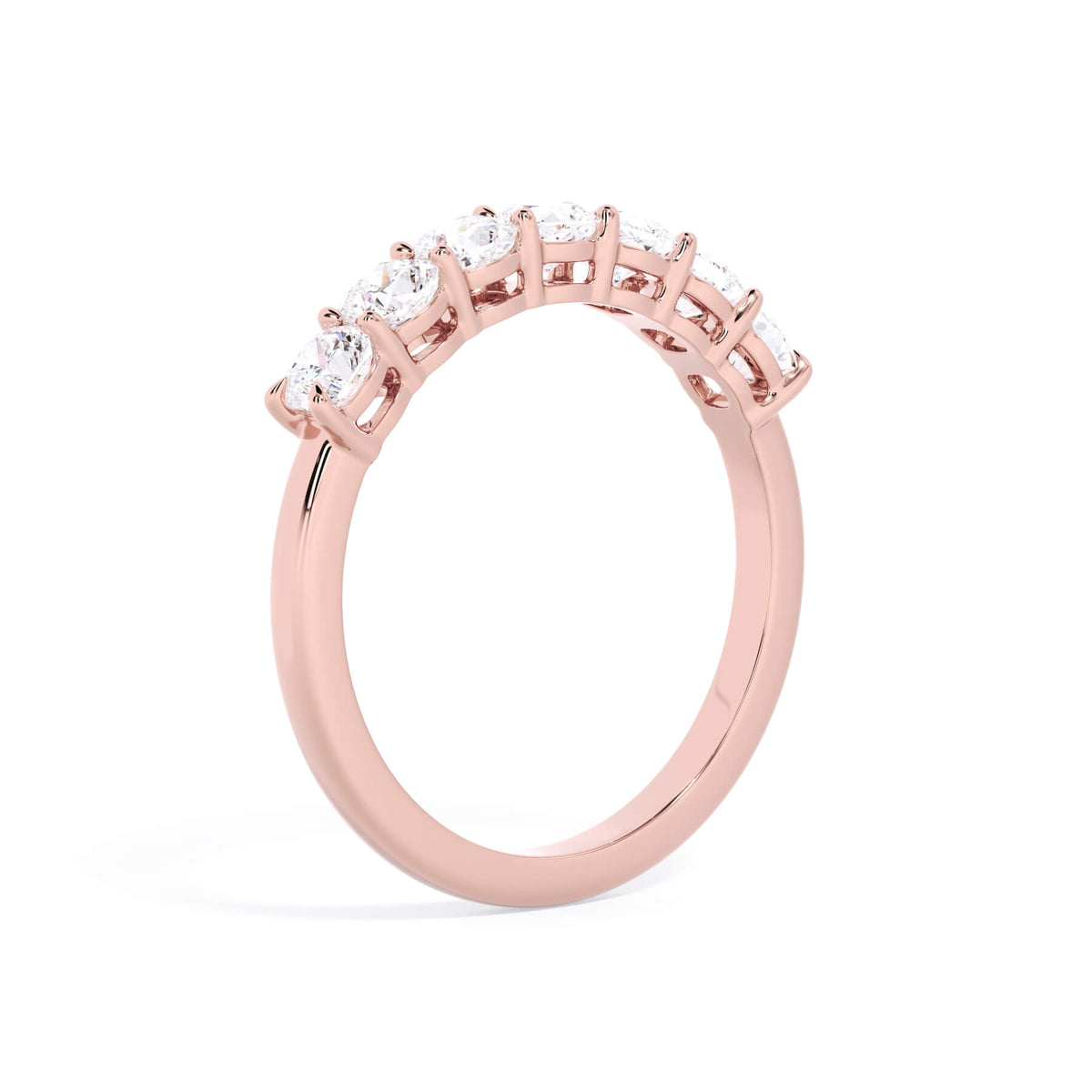 A picture of a seven stone diamond wedding ring with cushion cut diamonds that are shared prong set in rose gold on a white background with a slightly angled, through the finger view.