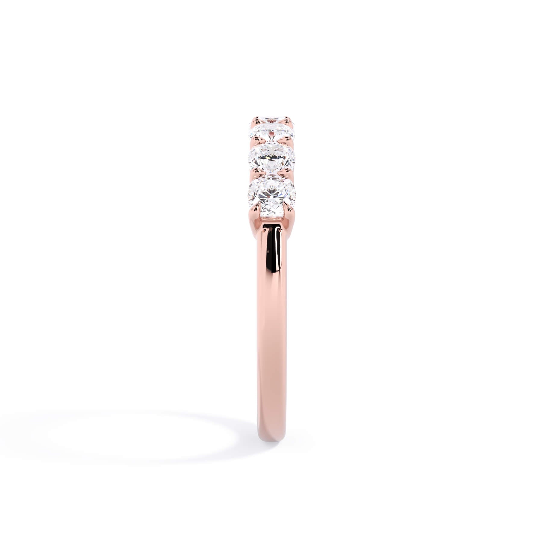 A picture of a seven stone diamond wedding ring with cushion cut diamonds that are shared prong set in rose gold on a white background with a side profile view.