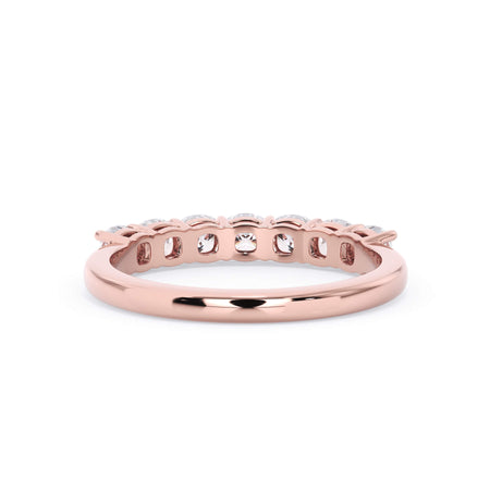 A picture of a seven stone diamond wedding ring with cushion cut diamonds that are shared prong set in rose gold on a white background with a view of the underside of the ring.