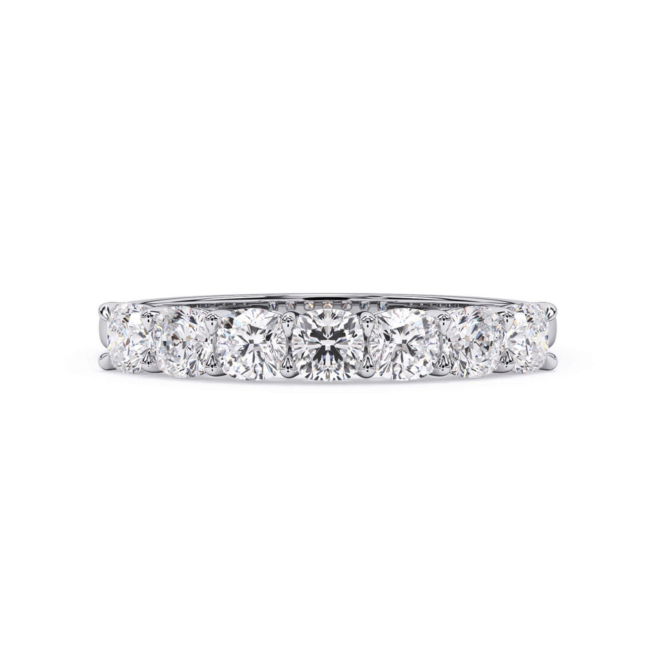 A picture of a seven stone diamond wedding ring with cushion cut diamonds that are shared prong set in white gold or platinum on a white background with the ring facing forward, lying down.