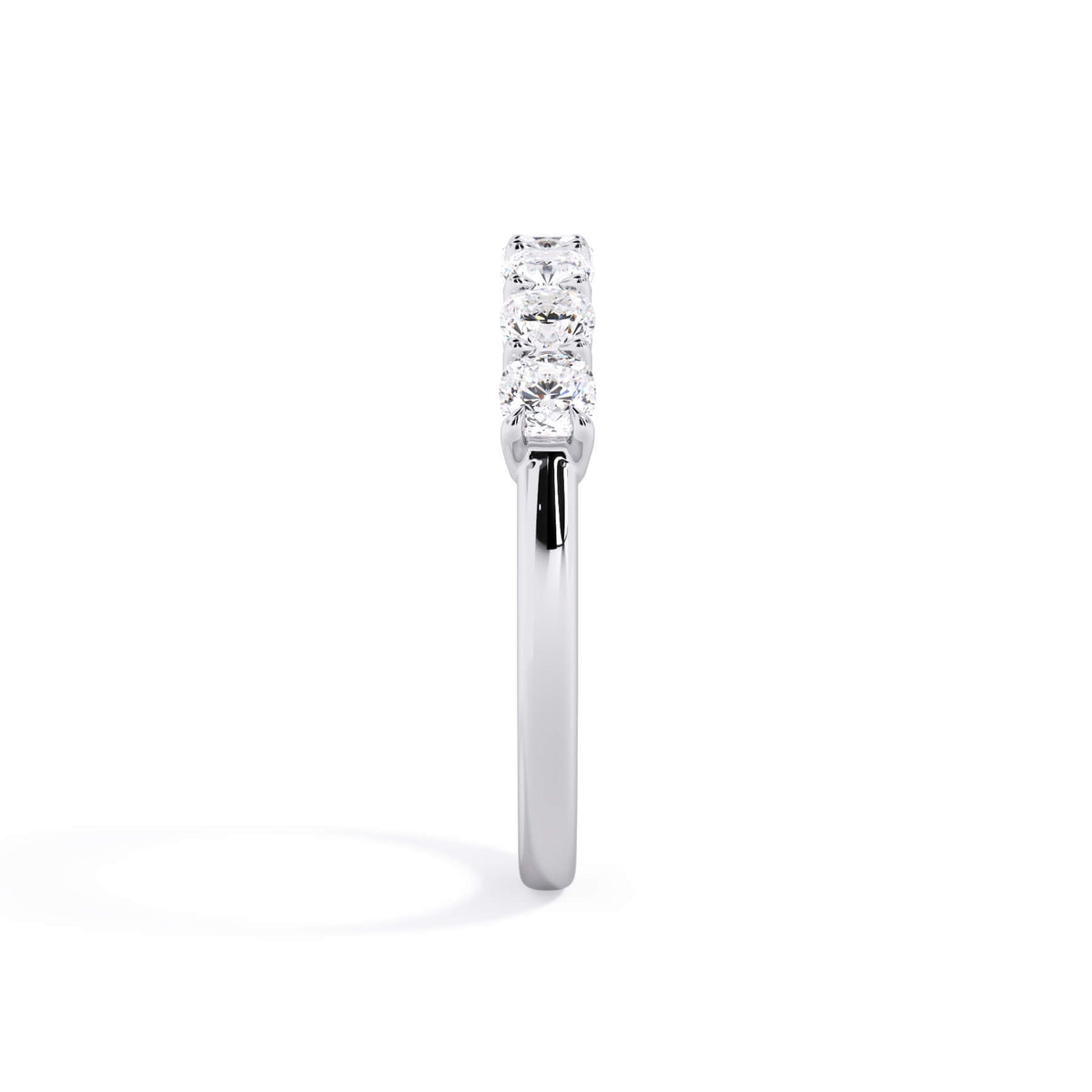 A picture of a seven stone diamond wedding ring with cushion cut diamonds that are shared prong set in white gold or platinum on a white background with a side profile view.