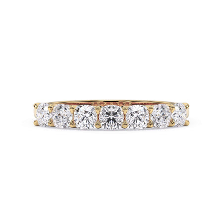 A picture of a seven stone diamond wedding ring with cushion cut diamonds that are shared prong set in yellow gold on a white background with the ring facing forward, lying down.